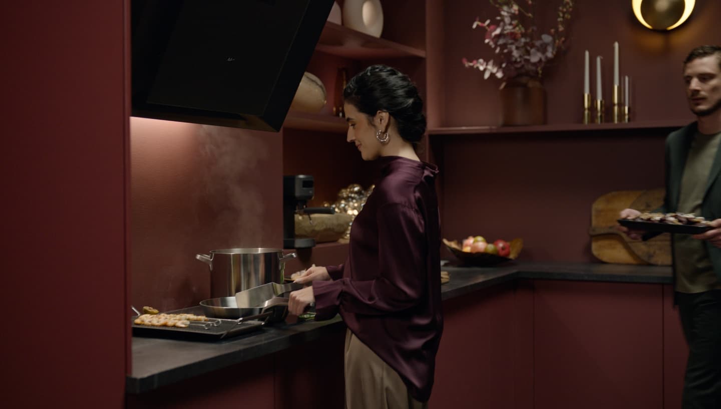 En kvinde og en mand laver mad i et moderne køkken.