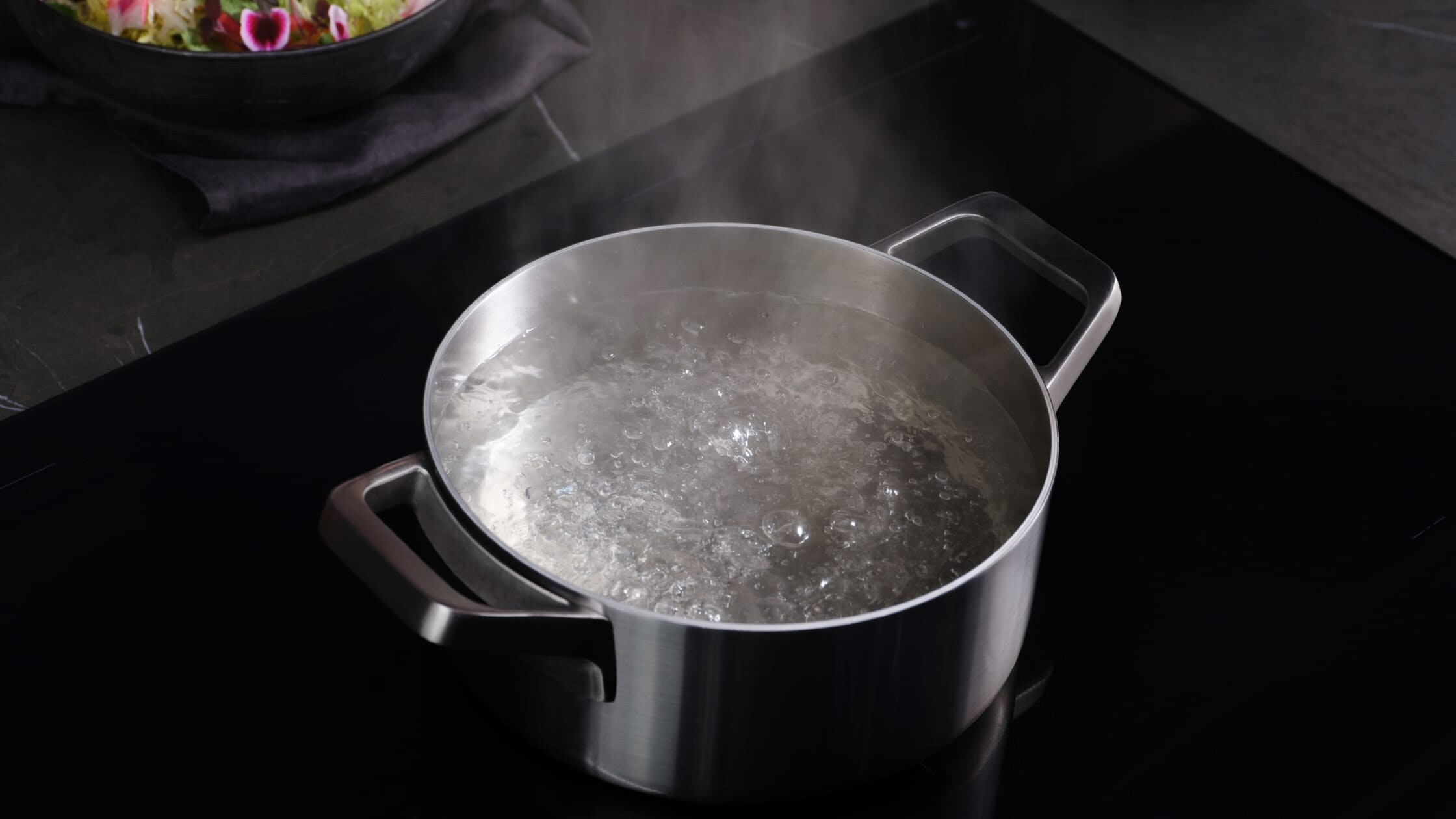 En gryde med kogende vand på en induktionskogeplade.