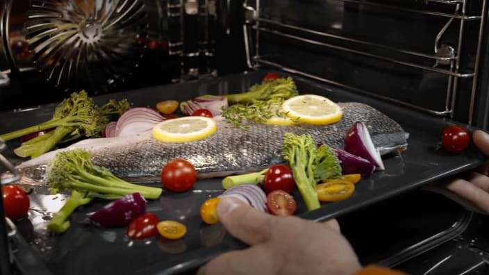 Tilberedt fisk tages ud af ovnen