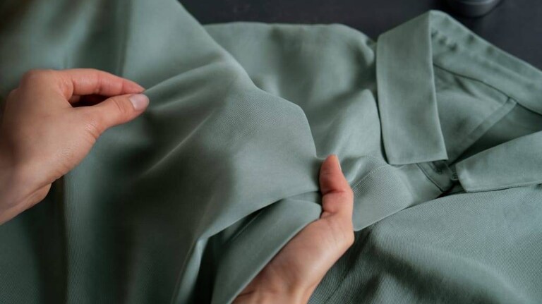 Hænder der undersøger en grøn skjorte.