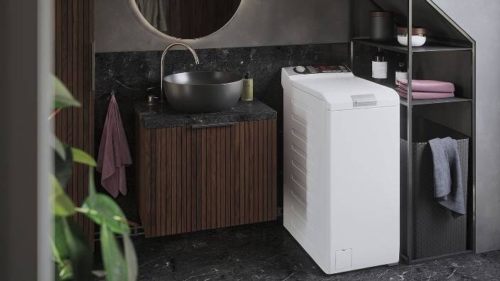 En topbetjent vaskemaskine i et lille vaskerum.