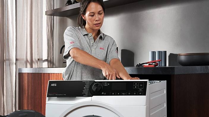 Kvinde reparerer vaskemaskine